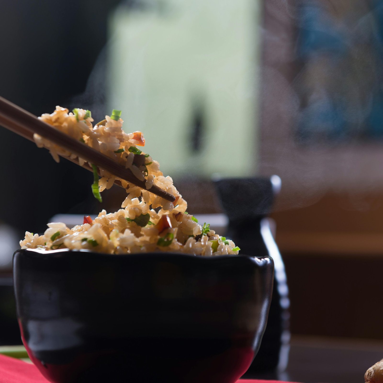 Delicious steaming fried rice in a black ceramic bowl with chopsticks, perfect for an appetizing meal.