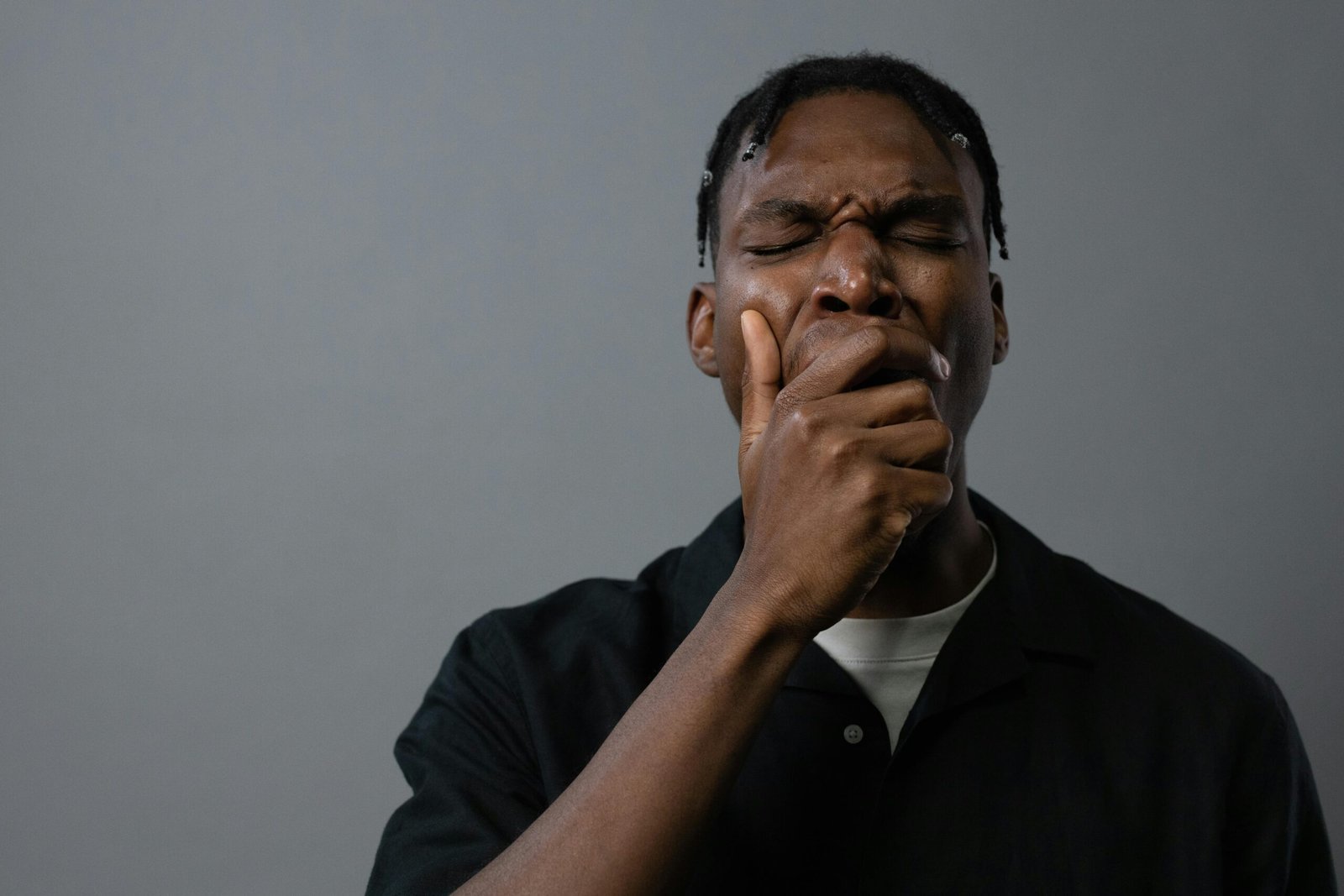 Portrait of a tired man yawning with hand on mouth, showing fatigue and exhaustion.