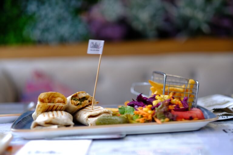 A diabetes-friendly fast food meal featuring a grilled chicken wrap, side salad, and french fries on a restaurant plate.